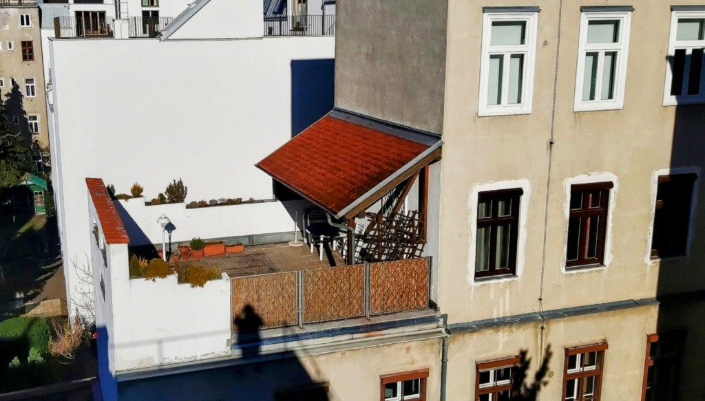Terrasse mit ausfahrbarem Vordach auf einem mehrstöckigen Wohnbau.